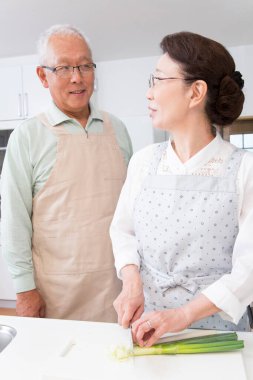 Yaşlı çift evde birlikte yemek pişiriyor. 