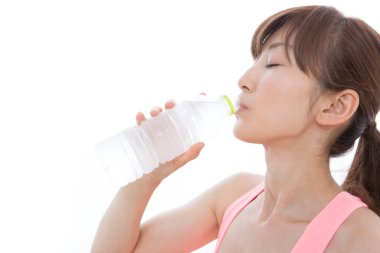 Genç sağlıklı Asyalı kadın egzersizden sonra şişeden su içiyor.