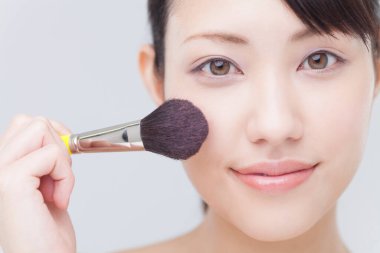 Makyaj yapan genç bir kadın.