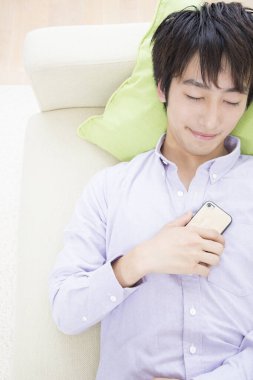 Genç adam akıllı telefonla rahatlıyor.