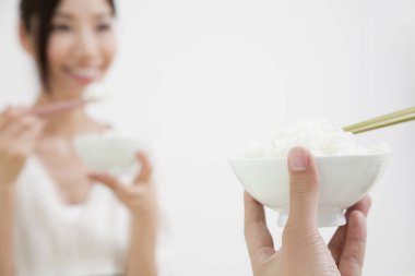 Asyalı kadın ve erkek birlikte yemek yiyorlar.