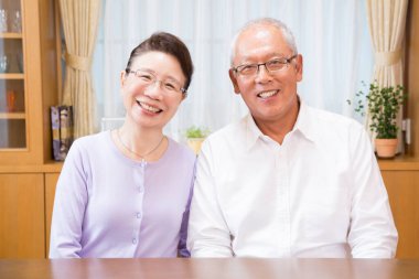 Masadaki Asyalı yaşlı çiftin portresi. 