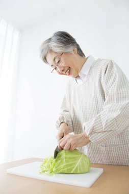 Kadın mutfakta lahana kesiyor.