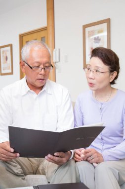 Yaşlı bir çift bir odada doküman okuyor. 