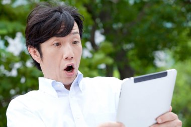 Asyalı genç adam tablet bilgisayar kullanıyor