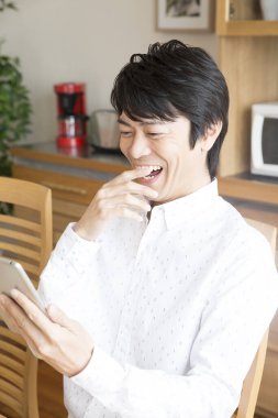 Tabletli genç adam masada oturuyor.