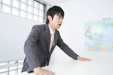 Japanese teacher in casual suit giving a lecture, standing close to blackboard  clipart