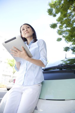 Tablet bilgisayarı olan kadın arabanın yanında bekliyor.