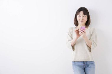 Asyalı kadın evde akıllı telefon kullanıyor. 