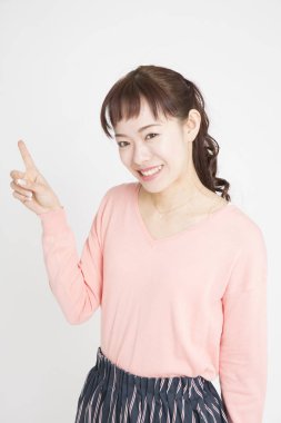 Beyaz arka planda parmağı olan Asyalı genç bir kadının portresi.