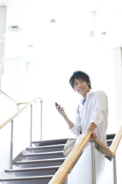 Genç adam koridorda cep telefonu kullanıyor.