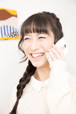 Güzel Asyalı genç bir kadın telefonda konuşuyor.