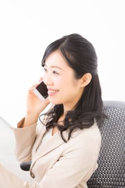 Genç bayan ofiste otururken akıllı telefon kullanıyor. 