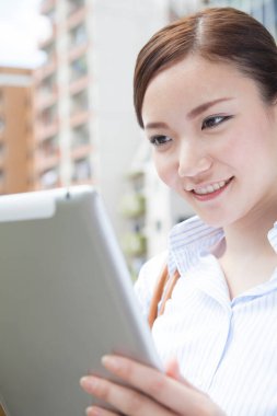 Köprüde duran tabletli genç Japon kadının portresi.