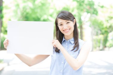 Asyalı kadın beyaz kağıtlı bir işaret göster.