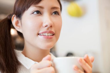 Kafede kahve fincanı olan genç bir kadın. 