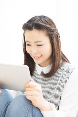 Evde tablet bilgisayar kullanan genç bir kadın.