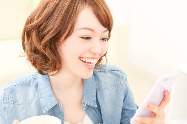 Evde cep telefonu kullanan güzel bir Japon kadın.