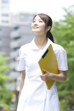 Kadın doktor parkta beyaz üniforma giyiyor. 