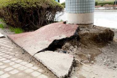 Çimenli beton direğin yanındaki kaldırımda hasar var.