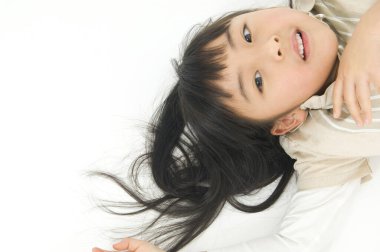 Beyaz zeminde yatan Asyalı küçük kız.