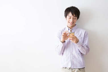 Gülümseyen ve akıllı telefon kullanan genç adamın portresi