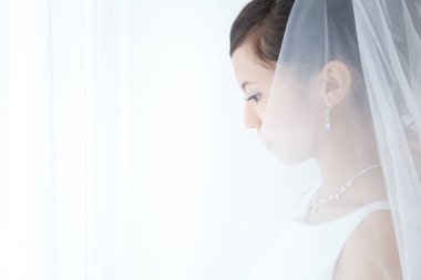 Gelinlik giymiş bir kadın aşağıya bakıyor.