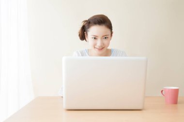 Masada oturan ve bilgisayarda çalışan genç bir kadın.