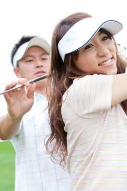 Antrenörüyle birlikte Asyalı kadın golfçü.