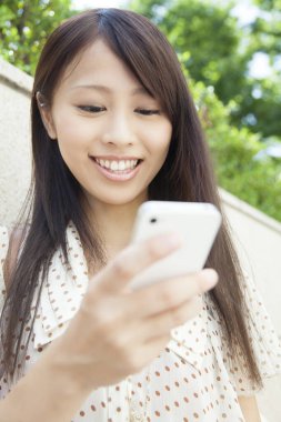 Sokakta akıllı telefon kullanan güzel Japon kadın.