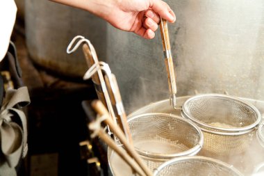 Erişte süzgecini kaynayan tencerenin üstünde tut.