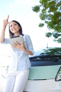 Tablet bilgisayarı olan kadın arabanın yanında bekliyor.