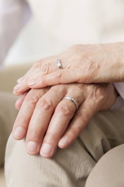 Kıdemli kadın bir erkeğin elini tutuyor.