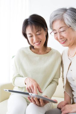 Yetişkin kızıyla dijital tablet kullanan yaşlı bir kadın. 