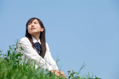 Kadın çimenlerde dinlenirken yukarı bakıyor.