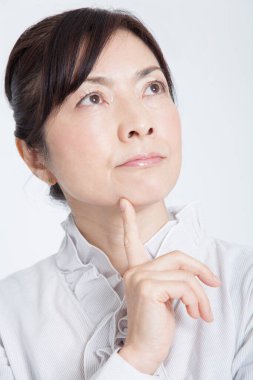 Beyaz arka planda düşünen Asyalı kadına yakın çekim 