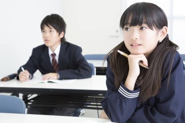 Okul üniformalı genç Asyalı öğrenciler masa başında çalışıyor, yüksek kalite fotoğraf.