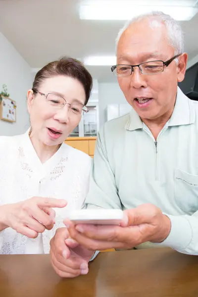 stock image senior asian couple looking at smartphone 