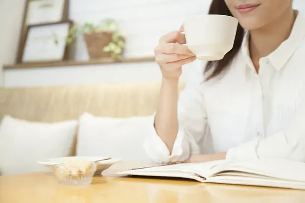 young woman drinking coffee and reading book