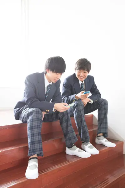Dos Asiático Jóvenes Chicos Escuela Uniforme Usando Móvil Teléfonos —  Fotos de Stock