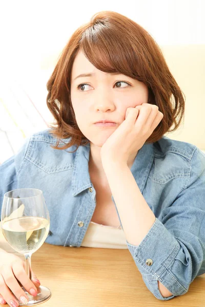 portrait of sad Asian woman using smartphone while drinking wine at home