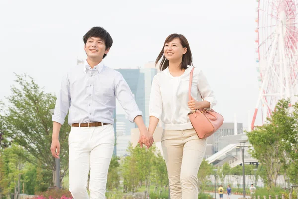 happy couple of young japanese couple walking together in park