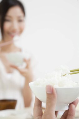 Asyalı kadın ve erkek birlikte yemek yiyorlar.