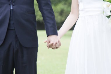 Damat ve gelin parkta el ele tutuşuyorlar.