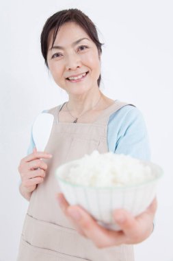 Asyalı kadın pilavlı kase tutuyor.