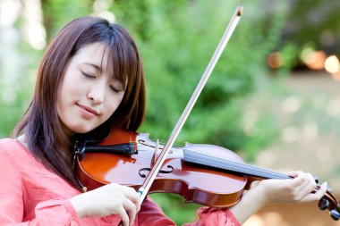 Kemanı olan genç Asyalı kadın.