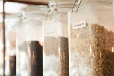 Cam kavanozlarda çeşitli kurutulmuş bitkisel malzemeler var.