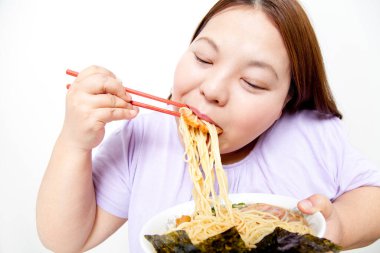 Şişman Asyalı kadın erişte yiyor. Stüdyo resmi