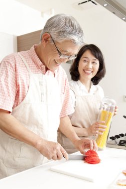 Asyalı çift evdeki mutfakta yemek pişiriyor.