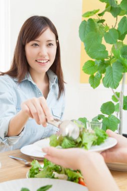 Genç kadın tabağa sebze salatası koyuyor. 